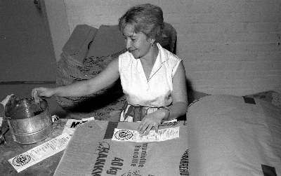 Nainen liimaa etikettejä rehusäkkkeihin Turun tehtaalla