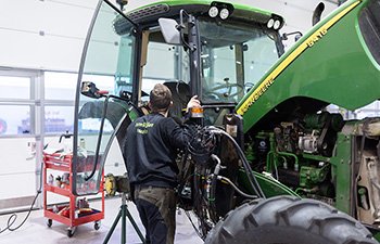 Hankkijan huoltomies huoltaa iäkkäämpää Jontikan traktoria.
