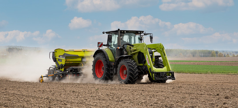 Claas-traktori vetää perässään Junkkarin kylvölannoitinta.